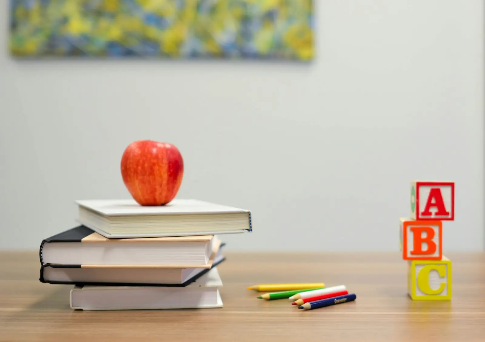 Bücherstapel mit Apfel und Buchstabenwürfeln auf einem Tisch
